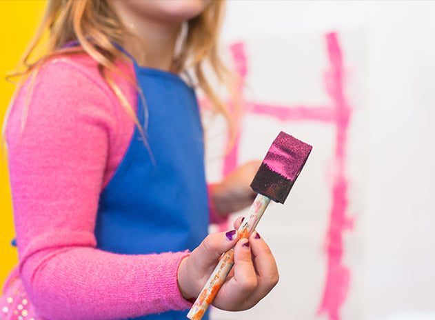 Girl painting with pink paint on canvas