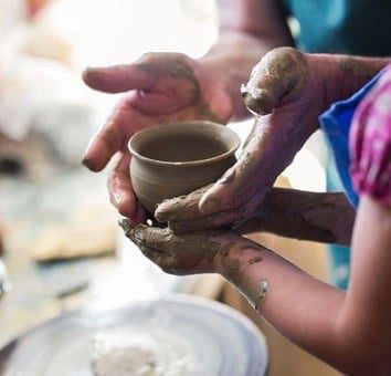 Clay Pot Being Formed by Artist and Child